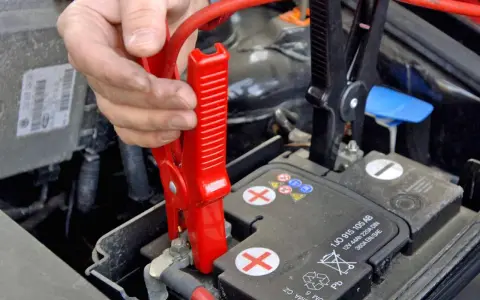 Starthilfe Auto: Rote Klemme wird am Pluspol der Batterie befestigt. Die richtige Reihenfolge ist entscheidend für die Sicherheit.