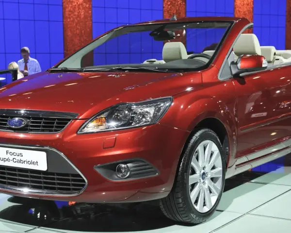 Roter Ford Focus Coupé-Cabriolet auf einer Messe. Ein Blick auf den **Ford Focus Wartungsplan** hilft, diesen Wagen in Topform zu halten.