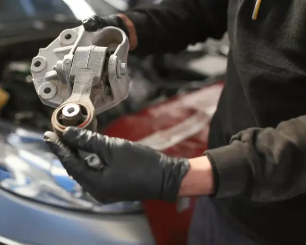 Mechaniker hält ein defektes Motorlager in der Hand, das ausgetauscht werden muss.