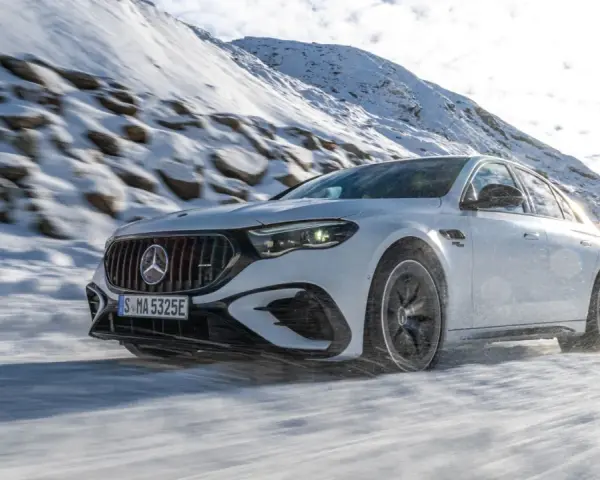 Weißer Mercedes-AMG mit 4MATIC fährt durch verschneite Berglandschaft.