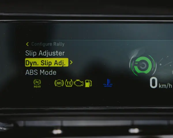 Fahrzeugdisplay zeigt Einstellungen für Traktionskontrolle (TC) und ABS. "Dyn. Slip Adj." ist hervorgehoben.