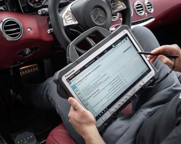 Diagnosegerät im luxuriösen Mercedes-Innenraum. Ein Techniker prüft die Daten, um die Service b Mercedes Kosten zu ermitteln.