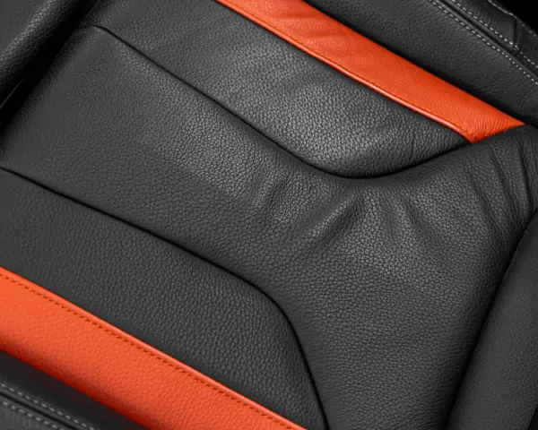 Detailaufnahme eines schwarzen Ledersitzes mit orangefarbenen Akzenten. Perfekt für die Leder reinigen Pflege.