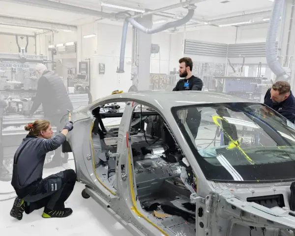 Mitarbeiter arbeiten an einem Auto-Chassis. Sie sind Teil eines Teams, das sich mit der Frage beschäftigt, was OEMs sind und wie sie in der Automobilproduktion eingesetzt werden.