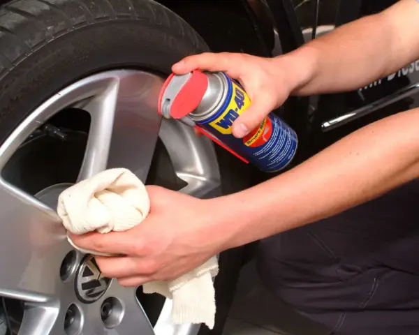 Person reinigt Felgen mit WD-40 und Tuch. Ein Hausmittel für glänzende Felgen.