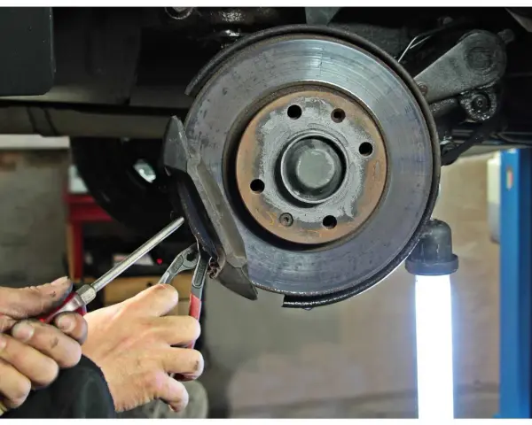 Mechaniker führt eine Inspektion am Bremssattel eines Mercedes durch. Der Service A steht an.