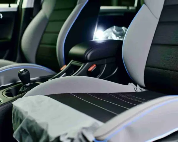 Detailaufnahme des Innenraums eines Autos, mit Fokus auf die Sitze. Die Sitze sind zweifarbig, grau und schwarz, mit blauen Akzenten. Sie scheinen bereit für die **ledersitze reparieren** zu sein.