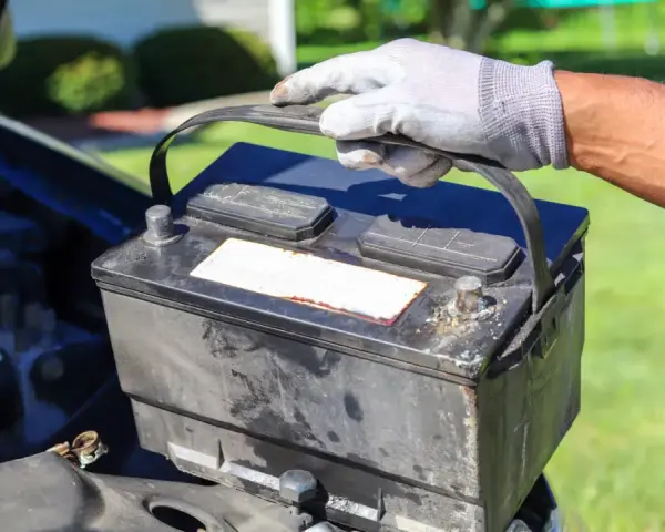 Gefährliche alte Autobatterie wird vorsichtig herausgehoben. Die richtige Entsorgung ist wichtig.