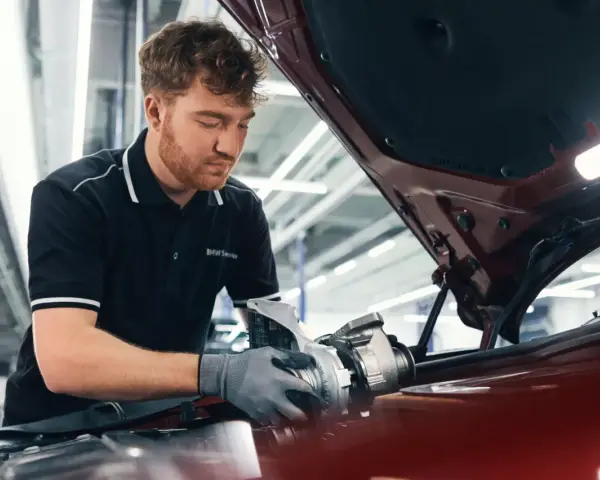 Mechaniker mit BMW Service Polohemd arbeitet an einem Turbolader für ein BMW CBS Fahrzeug.