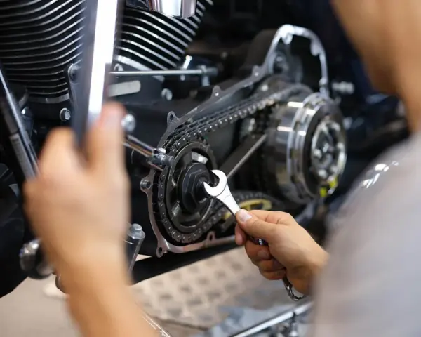 Mechaniker repariert Motorrad-Steuerkette. Die Kosten für den Wechsel der Steuerkette sind hier ein wichtiger Faktor.