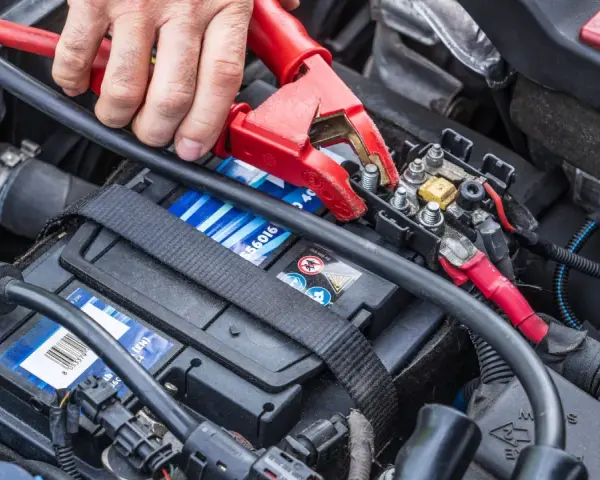 Starthilfe für eine leere Autobatterie: Rote und schwarze Klemmen werden an die Batterie angeschlossen.