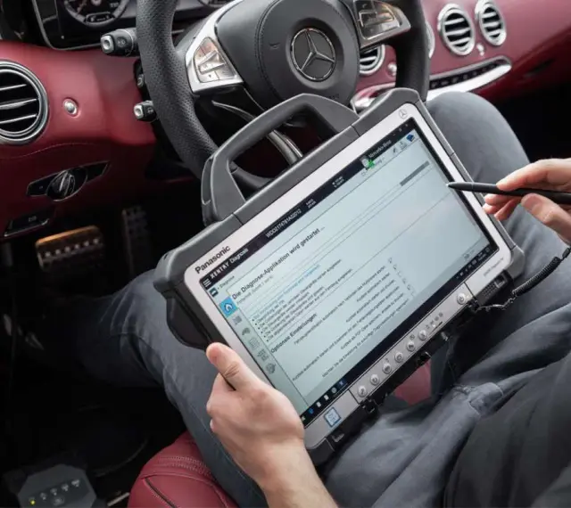 Diagnosegerät im luxuriösen Mercedes-Innenraum. Ein Techniker prüft die Daten, um die Service b Mercedes Kosten zu ermitteln.