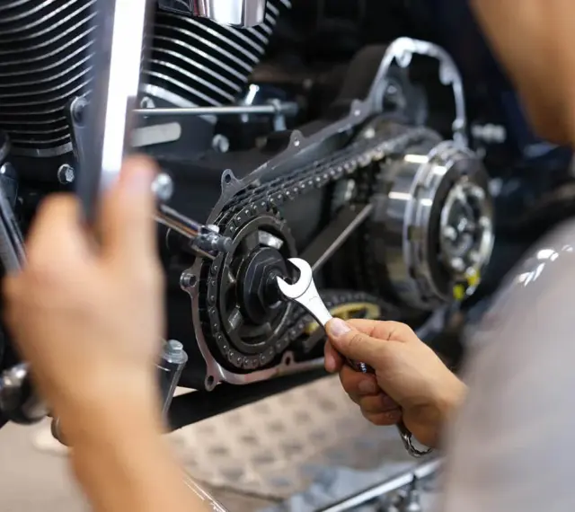 Mechaniker repariert Motorrad-Steuerkette. Die Kosten für den Wechsel der Steuerkette sind hier ein wichtiger Faktor.