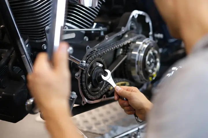 Mechaniker repariert Motorrad-Steuerkette. Die Kosten für den Wechsel der Steuerkette sind hier ein wichtiger Faktor.