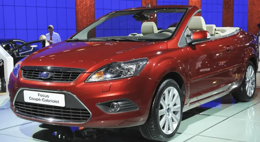 Roter Ford Focus Coupé-Cabriolet auf einer Messe. Ein Blick auf den **Ford Focus Wartungsplan** hilft, diesen Wagen in Topform zu halten.