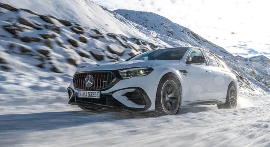 Weißer Mercedes-AMG mit 4MATIC fährt durch verschneite Berglandschaft.