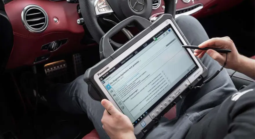 Diagnosegerät im luxuriösen Mercedes-Innenraum. Ein Techniker prüft die Daten, um die Service b Mercedes Kosten zu ermitteln.