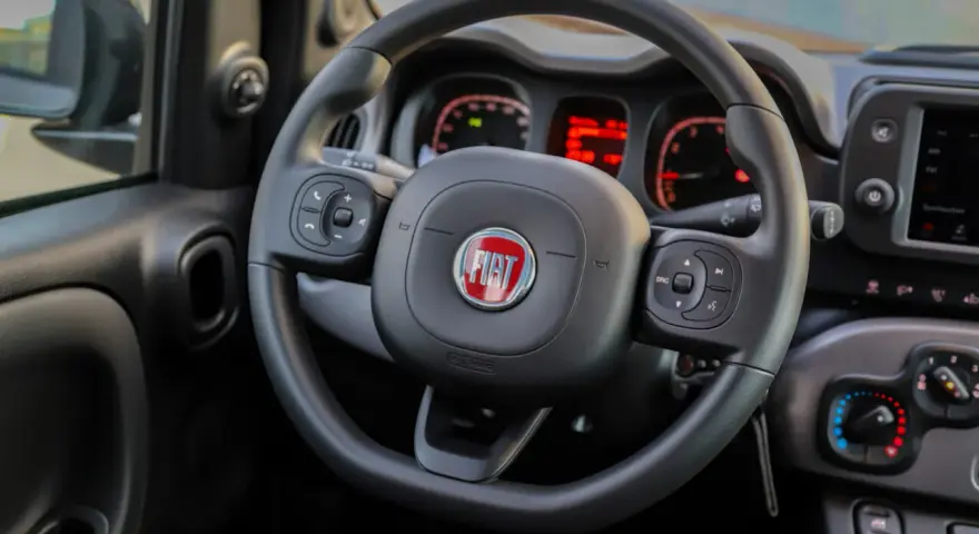 Lenkrad eines Fiat Panda. Die Instrumententafel zeigt rote Warnleuchten, vielleicht für den **Fiat Panda Reifendruck**.