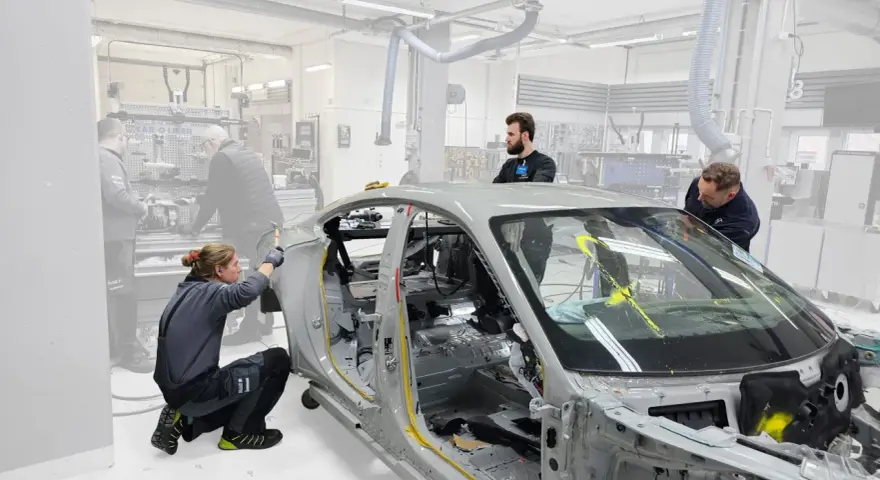 Mitarbeiter arbeiten an einem Auto-Chassis. Sie sind Teil eines Teams, das sich mit der Frage beschäftigt, was OEMs sind und wie sie in der Automobilproduktion eingesetzt werden.