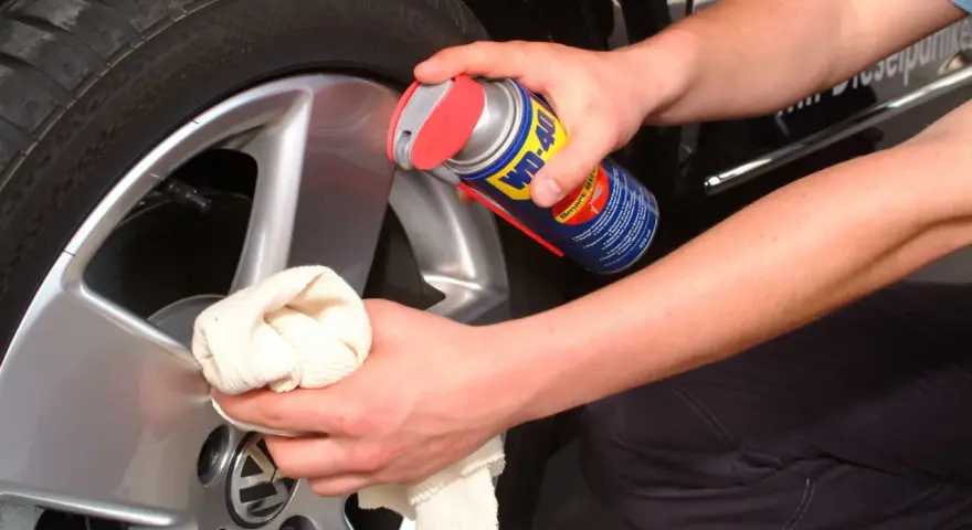 Person reinigt Felgen mit WD-40 und Tuch. Ein Hausmittel für glänzende Felgen.