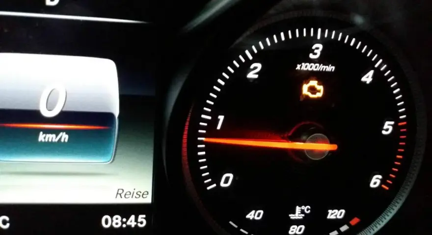 Mercedes-Armaturenbrett mit leuchtender Motorkontrollleuchte. Tachometer zeigt 0 km/h, daneben die Uhrzeit 08:45.