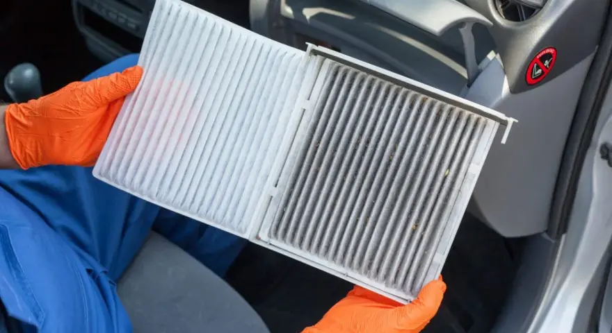 Person mit orangefarbenen Handschuhen hält einen neuen und einen schmutzigen Innenraumfilter. Zeit, den Innenraumfilter zu wechseln für saubere Luft im Auto.