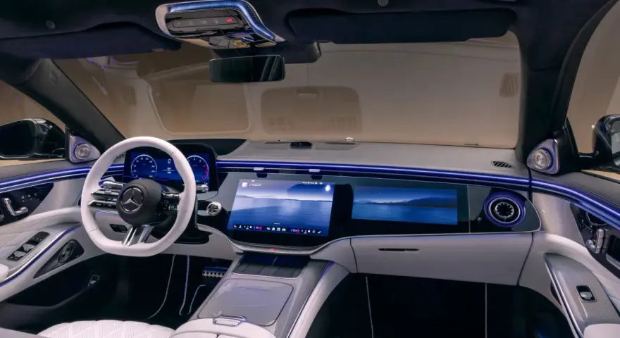 Luxuriöses Auto-Armaturenbrett mit großem Touchscreen, weißem Lenkrad und Ambientebeleuchtung.