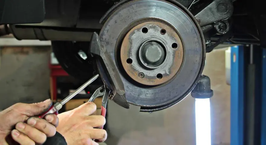 Mechaniker führt eine Inspektion am Bremssattel eines Mercedes durch. Der Service A steht an.