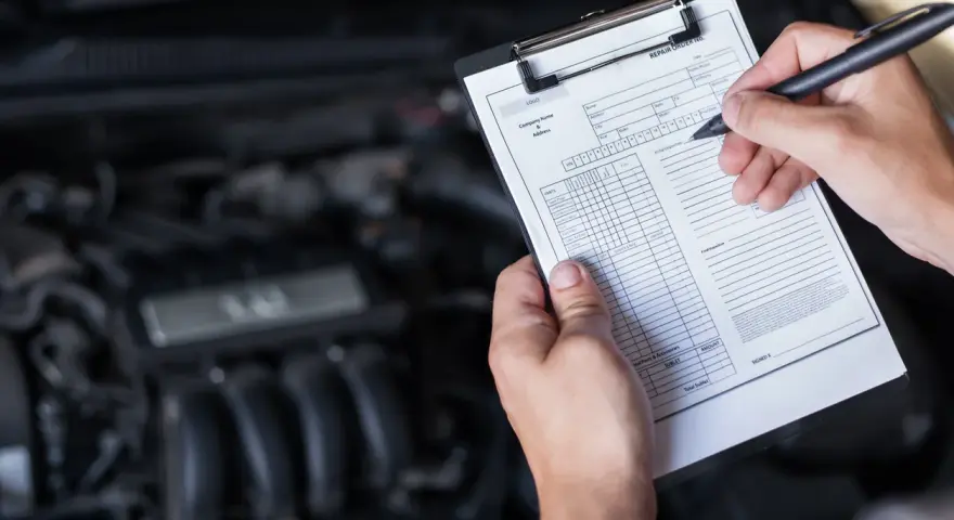 Mechaniker prüft den Motor und füllt ein Formular aus, um die durchsicht auto kosten zu ermitteln.
