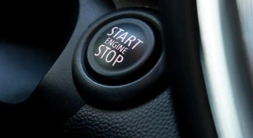 Nahaufnahme eines Start/Stop-Knopfes im Auto. Der Knopf ist beleuchtet und zeigt die Worte "START ENGINE STOP".