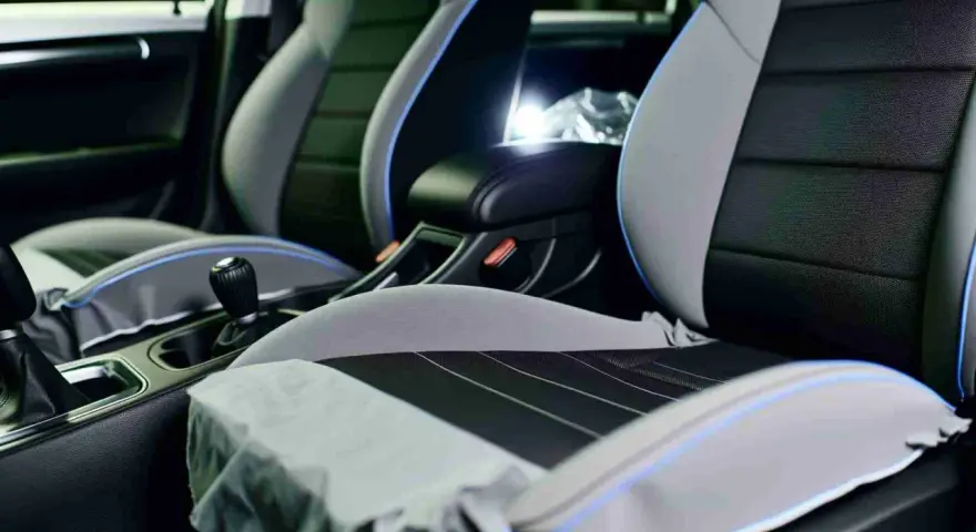 Detailaufnahme des Innenraums eines Autos, mit Fokus auf die Sitze. Die Sitze sind zweifarbig, grau und schwarz, mit blauen Akzenten. Sie scheinen bereit für die **ledersitze reparieren** zu sein.
