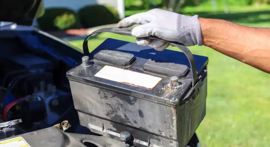 Gefährliche alte Autobatterie wird vorsichtig herausgehoben. Die richtige Entsorgung ist wichtig.