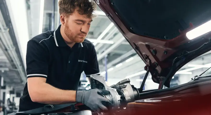 Mechaniker mit BMW Service Polohemd arbeitet an einem Turbolader für ein BMW CBS Fahrzeug.