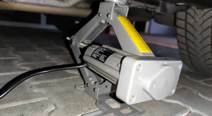 Elektrischer Wagenheber hebt das Auto an, um Reifen mit Reifendrucksensor selber zu wechseln.