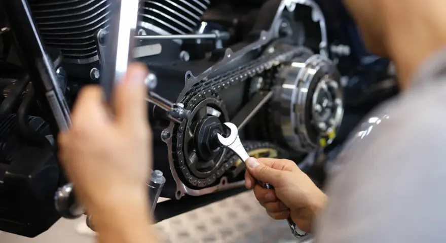 Mechaniker repariert Motorrad-Steuerkette. Die Kosten für den Wechsel der Steuerkette sind hier ein wichtiger Faktor.