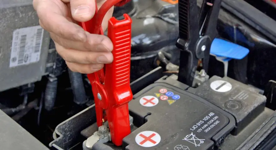 Starthilfe Auto: Rote Klemme wird am Pluspol der Batterie befestigt. Die richtige Reihenfolge ist entscheidend für die Sicherheit.