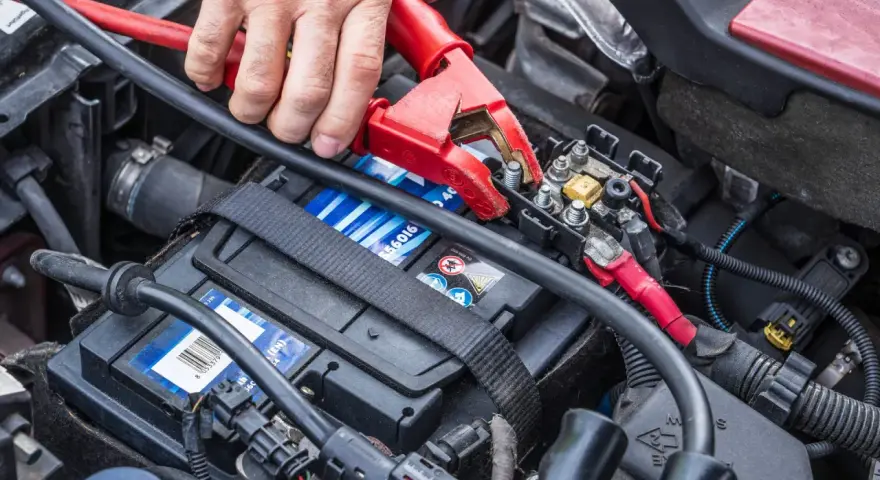 Starthilfe für eine leere Autobatterie: Rote und schwarze Klemmen werden an die Batterie angeschlossen.