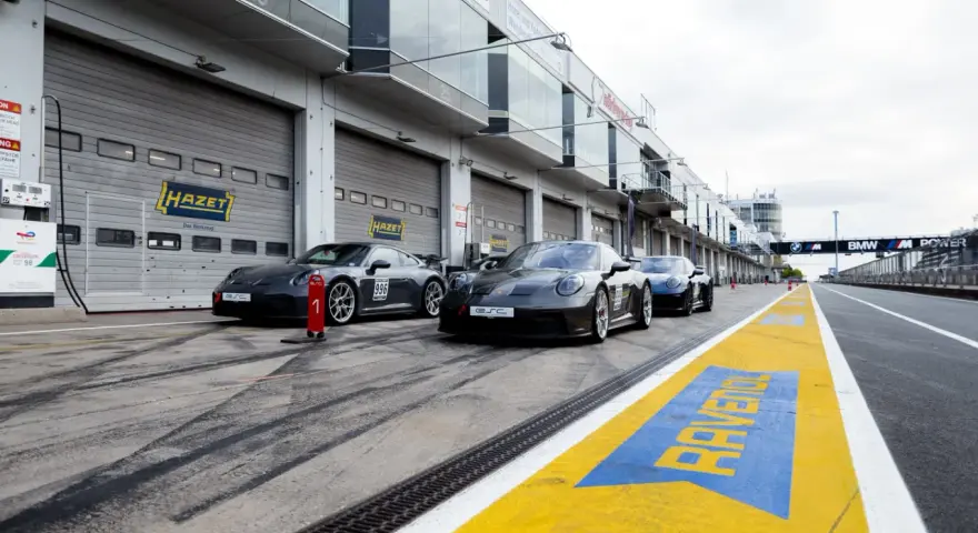 Porsche-Rennwagen in Boxengasse. Hier kann man pitstop teile selber mitbringen. Gelbe Markierungen auf dem Asphalt.