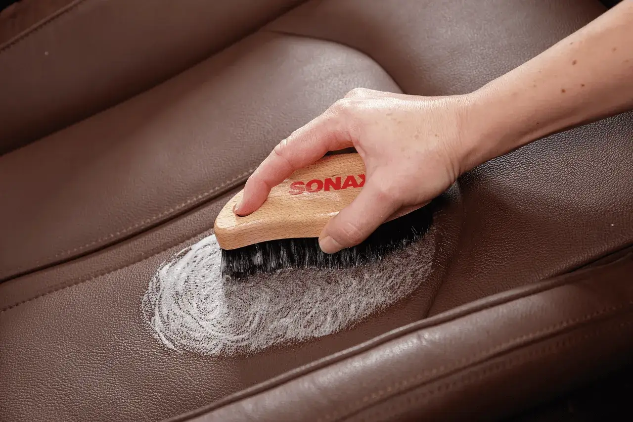 Hand b&uuml;rstet braunes Leder mit Schaum, um es aufzubereiten.