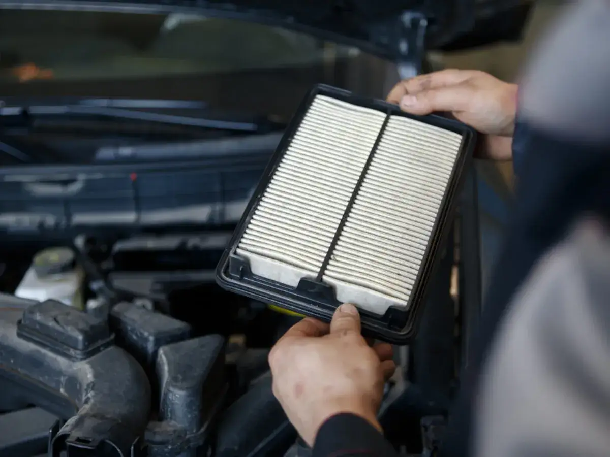 Hände halten einen neuen Innenraumfilter bereit, um ihn im Auto zu wechseln.