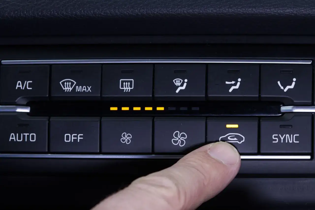 Finger dr&uuml;ckt auf Klimaanlagen-Symbol im Cockpit Auto. Gelbe Lichter zeigen die Einstellungen an.