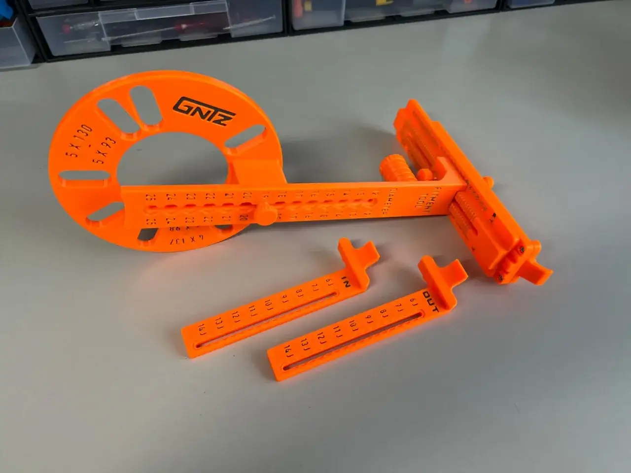 Ein orangefarbenes Werkzeug hilft beim felgenbreite messen. Es hat Skalen und zwei zus&auml;tzliche Messschieber.