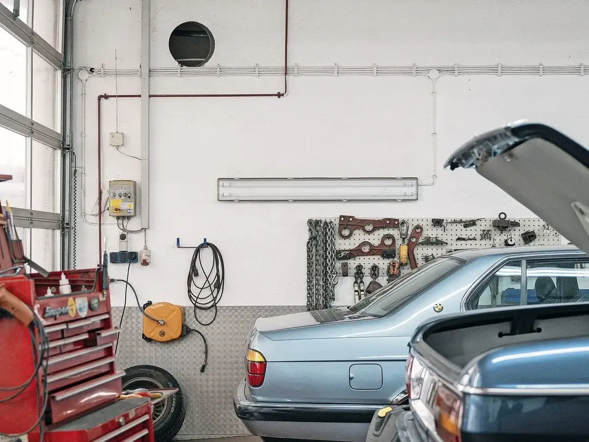 Werkstatt bekommt Ersatzteil nicht. Werkzeugwand, Autos und Kabeltrommel.
