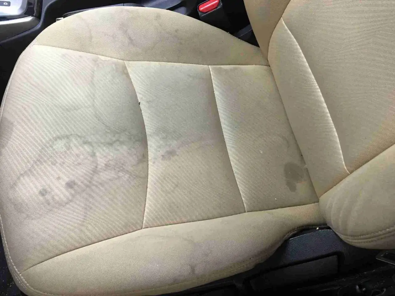 Helle Stoffpolsterung des Autositzes mit deutlichen wasserflecken.