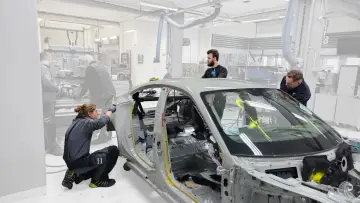 Mitarbeiter arbeiten an einem Auto-Chassis. Sie sind Teil eines Teams, das sich mit der Frage beschäftigt, was OEMs sind und wie sie in der Automobilproduktion eingesetzt werden.
