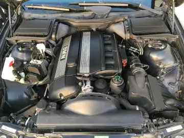 BMW Motorraum, bereit für die Inspektion. Der Motor ist sauber und alle Komponenten sind gut sichtbar.