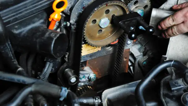 Ein Mechaniker arbeitet am Zahnriemenwechsel. Wann ist der richtige Zeitpunkt dafür?