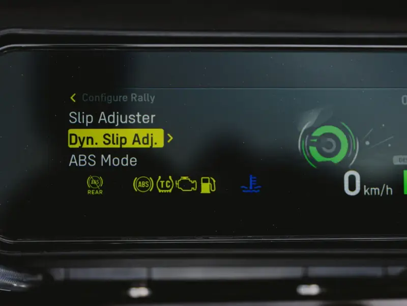Fahrzeugdisplay zeigt Einstellungen für Traktionskontrolle (TC) und ABS. "Dyn. Slip Adj." ist hervorgehoben.
