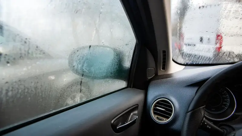 Beschlagene Autoscheiben innen reinigen. Ein Blick aus dem Auto zeigt beschlagene Scheiben und einen Außenspiegel.