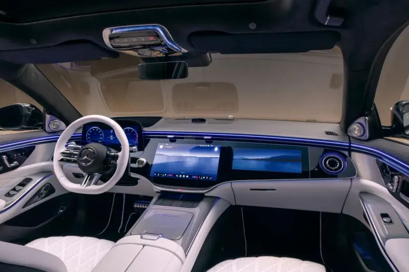 Luxuriöses Auto-Armaturenbrett mit großem Touchscreen, weißem Lenkrad und Ambientebeleuchtung.